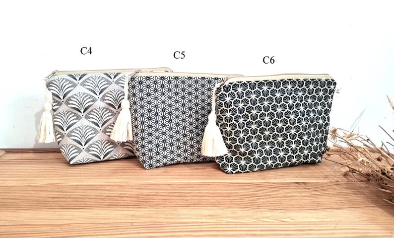May include: Three zippered pouches labeled C4, C5, and C6. The first features a grey and white fan pattern, the second a black and white geometric star print, and the third a black and white honeycomb design. Each pouch includes a cream tassel.