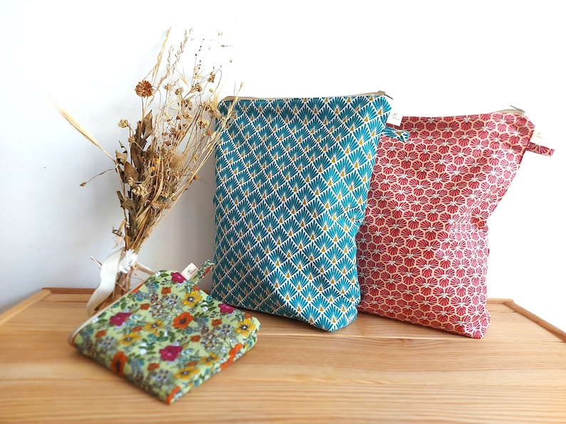 May include: Three fabric pouches in teal, red, and floral patterns. The teal pouch has a geometric design with gold accents. The red pouch features a repeating shell-like pattern. A small floral pouch is also present.