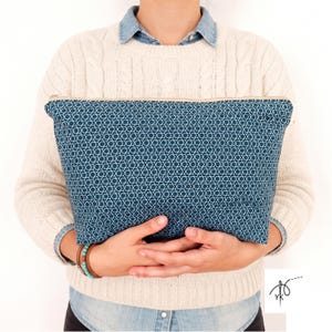 Può includere: Una pochette rettangolare con cerniera in tessuto blu ottanio scuro con un motivo geometrico bianco ripetuto di stelle a sei punte intrecciate. La pochette presenta una chiusura a zip di colore chiaro sul bordo superiore.