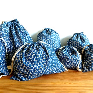 Pode incluir: Conjunto de sete sacos de cord&atilde;o azul e branco com um padr&atilde;o geom&eacute;trico. Os sacos s&atilde;o feitos de tecido e t&ecirc;m um fecho de cord&atilde;o.