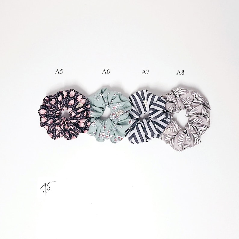 Pu&ograve; includere: Quattro elastici per capelli in tessuto in fila, ognuno con un motivo unico. Gli elastici sono etichettati A5, A6, A7 e A8. Gli elastici presentano motivi in nero, rosa, bianco e grigio. Gli elastici sono su sfondo bianco.