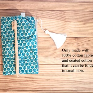 May include: A teal and white patterned fabric pouch with a zipper closure and a white tassel. A wooden toothbrush is inside the pouch. The text "Only made with 100% cotton fabric and coated cotton fabric that it can be folded to small size." is written below the pouch.