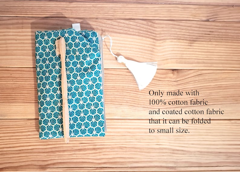 May include: A teal and white patterned fabric pouch with a zipper closure and a white tassel. A wooden toothbrush is inside the pouch. The text "Only made with 100% cotton fabric and coated cotton fabric that it can be folded to small size." is written below the pouch.