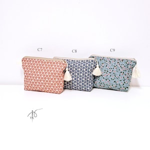 May include: Three rectangular zippered pouches with tassels. The first, labeled C7, is terracotta with a white fan pattern. The second, C8, is navy blue with a white fan pattern. The third, C9, is light blue with a small pink floral and green leaf print.