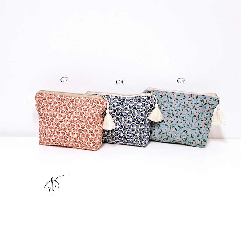 May include: Three rectangular zippered pouches with tassels. The first, labeled C7, is terracotta with a white fan pattern. The second, C8, is navy blue with a white fan pattern. The third, C9, is light blue with a small pink floral and green leaf print.
