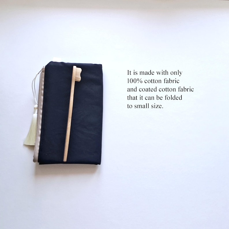May include: A navy blue travel case with a light-colored tassel and a wooden toothbrush. The text on the image reads: "It is made with only 100% cotton fabric and coated cotton fabric that it can be folded to small size."