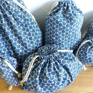 Pode incluir: Um conjunto de cinco sacos de cord&atilde;o azul e branco com um padr&atilde;o geom&eacute;trico. Os sacos s&atilde;o feitos de tecido e t&ecirc;m um fecho de cord&atilde;o branco.