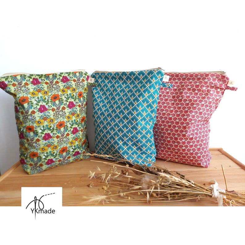 May include: Three fabric pouches with zipper closures. One pouch has a floral pattern with orange, pink, and yellow flowers on a green background. Another is teal with a geometric design. The third is red with a repeating pattern.