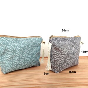 May include: Two zippered pouches featuring a geometric star pattern. One pouch is teal and the other is gray. Each has a beige zipper and a small white tassel. The gray pouch is labeled with dimensions of 20cm by 14cm by 5cm, which is approximately 7.9in by 5.5in by 2in.