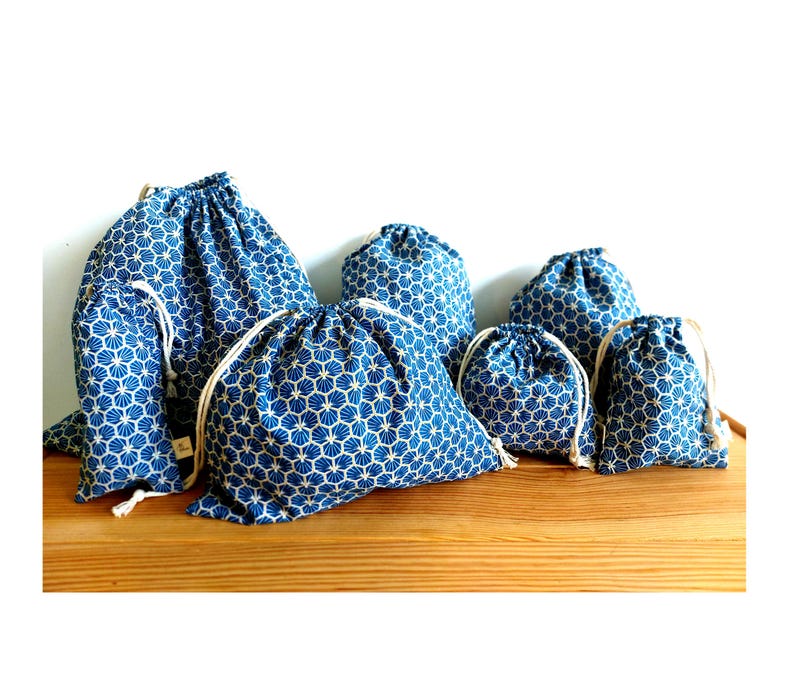 Pode incluir: Conjunto de sete sacos de cord&atilde;o de diferentes tamanhos, com padr&atilde;o azul e branco. Os sacos s&atilde;o feitos de tecido e t&ecirc;m um design geom&eacute;trico.