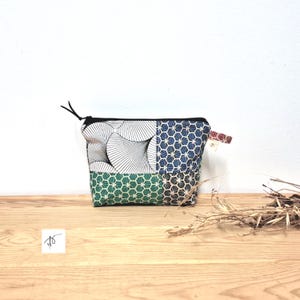 May include: A small, rectangular fabric pouch with a black zip and pull. The pouch is divided into three sections with different patterns: black and white geometric shapes, blue and white geometric shapes, and green and white geometric shapes.