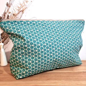May include: A teal zippered pouch with a white and teal geometric pattern. The pouch has a white tassel.