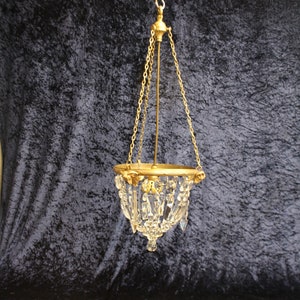 May include: A small gold-toned chandelier with crystal drops hanging from a chain.