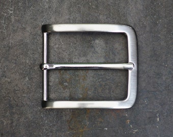 May include: A silver metal belt buckle with a smooth, polished finish.