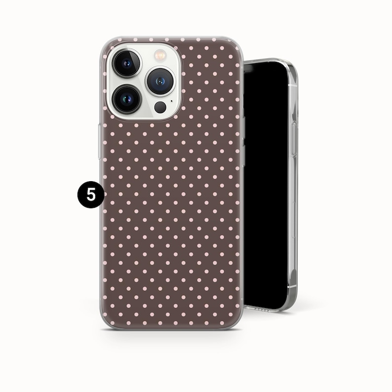 May include: A brown phone case with a pattern of small, evenly spaced pink polka dots. The case is on a smartphone, with the camera lenses visible. The phone's screen is black.