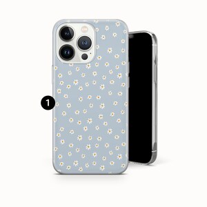 Pode incluir: Capa de telefone azul claro com um padr&atilde;o de margaridas. A capa tem uma borda transparente e &eacute; mostrada ao lado de um smartphone preto. As margaridas s&atilde;o brancas com centros amarelos.