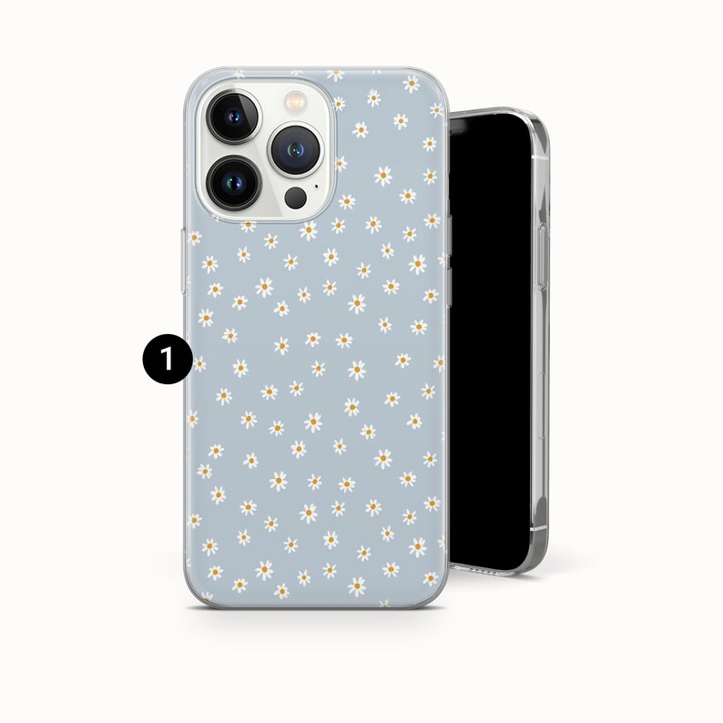 Pode incluir: Capa de telefone azul claro com um padr&atilde;o de margaridas. A capa tem uma borda transparente e &eacute; mostrada ao lado de um smartphone preto. As margaridas s&atilde;o brancas com centros amarelos.