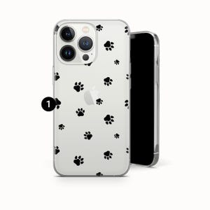 May include: Clear phone case with a pattern of black paw prints. The case is designed to fit a smartphone, with cutouts for the camera and buttons. The phone case is made of a transparent material, allowing the phone's color to show through.