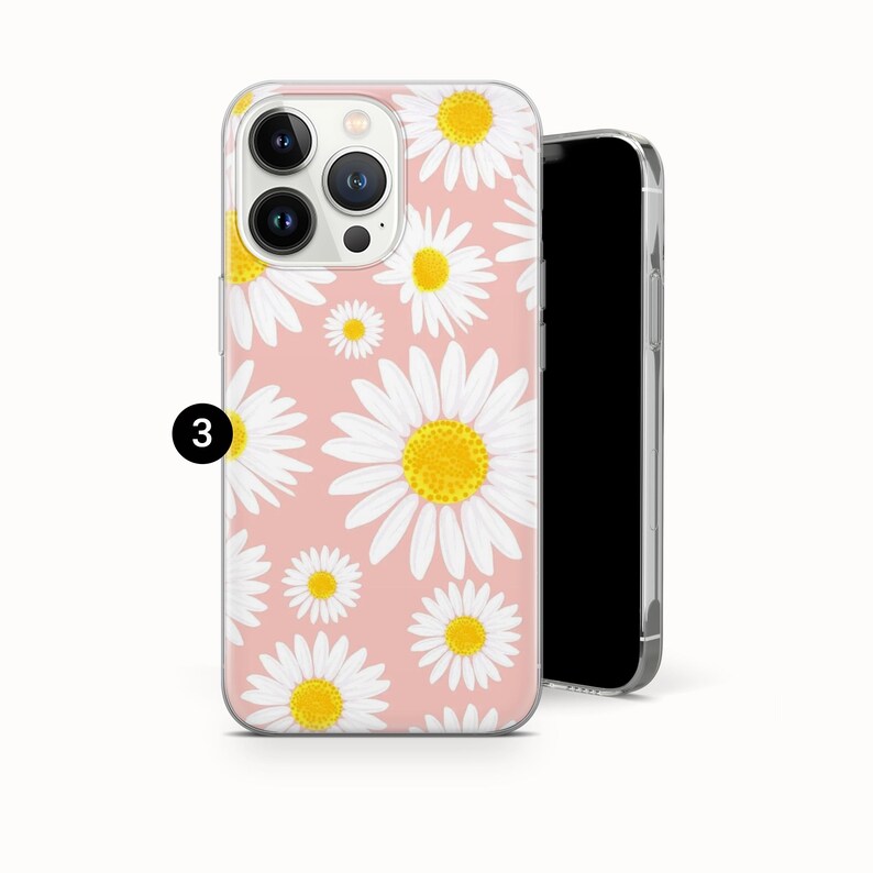 Pode incluir: Capa de telem&oacute;vel com fundo rosa e padr&atilde;o de margaridas brancas com centros amarelos. A capa, feita de material transparente e protetor, foi concebida para um smartphone. Um smartphone preto &eacute; mostrado ao lado da capa.
