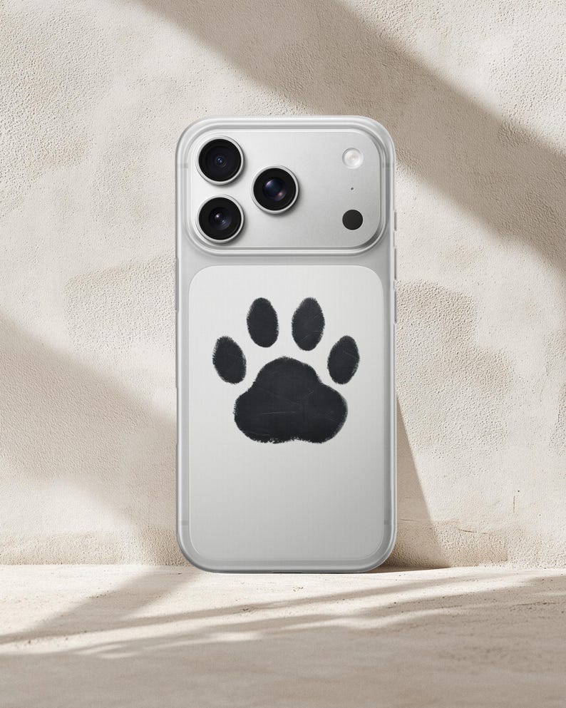 May include: Clear phone case with a black paw print design. The case has a clear border and a white backing with a large, black paw print in the center. The phone's camera lenses are visible at the top.