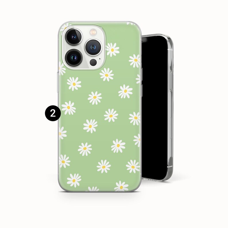 Pode incluir: Uma capa de telefone verde claro com um padr&atilde;o de margaridas. A capa tem uma borda transparente e apresenta m&uacute;ltiplas margaridas brancas com centros amarelos espalhados pela superf&iacute;cie. A capa do telefone &eacute; mostrada ao lado de um smartphone preto.