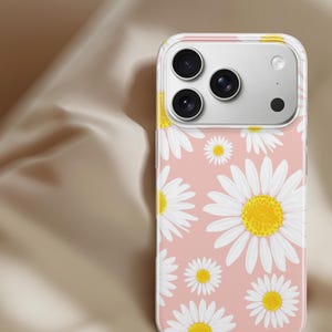 Pode incluir: Capa de telefone transparente com fundo rosa e um padr&atilde;o de margaridas brancas com centros amarelos. A capa cobre um telefone com tr&ecirc;s lentes de c&acirc;mera.