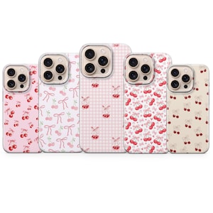 May include: Five different phone cases with a cherry and bow pattern. The cases are pink, white, and beige with a checkered pattern on one case.