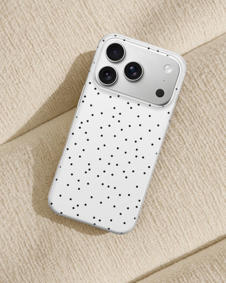 May include: A white phone case with a black polka dot pattern. The case has a clear border and a silver camera module with three lenses. The phone case is designed to fit a smartphone.