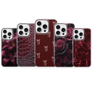 Może przedstawiać: Kolekcja pięciu etui na telefony o różnych wzorach. Etui mają wzory kwiatowe, kokardki i teksturowane w odcieniach bordowego i ciemnoczerwonego. Każde etui ma wycięcie na aparat i ochronny zderzak.