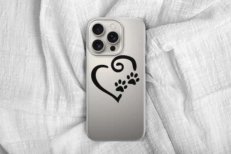 May include: A clear phone case featuring a black heart design with two paw prints. The case is shown on a white, textured fabric background. The phone case is designed to fit a smartphone.