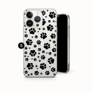May include: Clear phone case with a black paw print pattern. The case is designed to fit a smartphone and features a repeating pattern of paw prints. The phone case is shown next to a black smartphone.