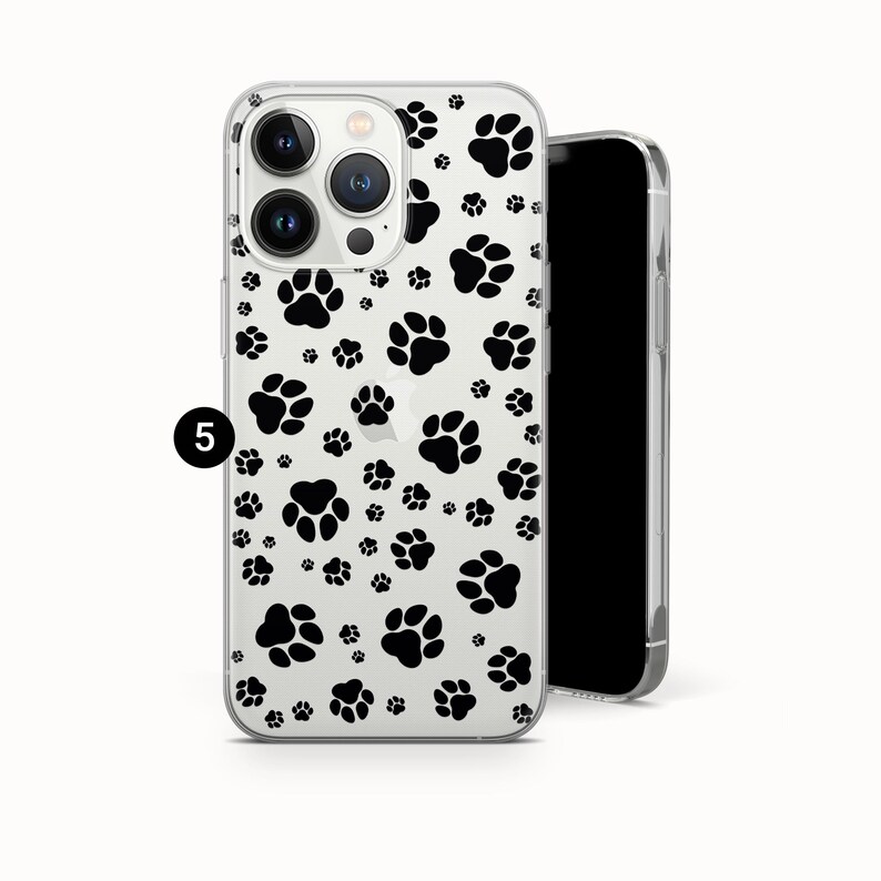 May include: Clear phone case with a black paw print pattern. The case is designed to fit a smartphone and features a repeating pattern of paw prints. The phone case is shown next to a black smartphone.