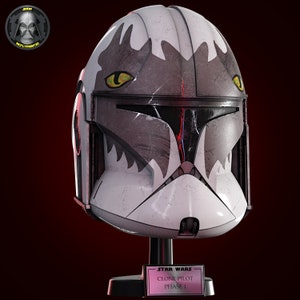 May include: A white and gray Star Wars Clone Pilot Phase 1 helmet with a black and red visor. The helmet has a wolf-like design with yellow eyes and a black base.