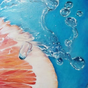 May include: A close-up of a grapefruit half submerged in water with bubbles rising to the surface. The grapefruit is a vibrant orange and red color, and the water is a bright blue.