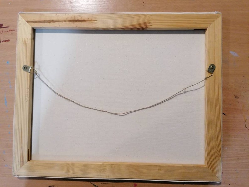 May include: The back of a wooden framed canvas painting with a string attached to two metal hooks for hanging.