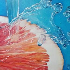 May include: A close-up of a grapefruit being rinsed under a stream of water. The water creates a spray of bubbles and droplets, highlighting the vibrant red and orange hues of the grapefruit.