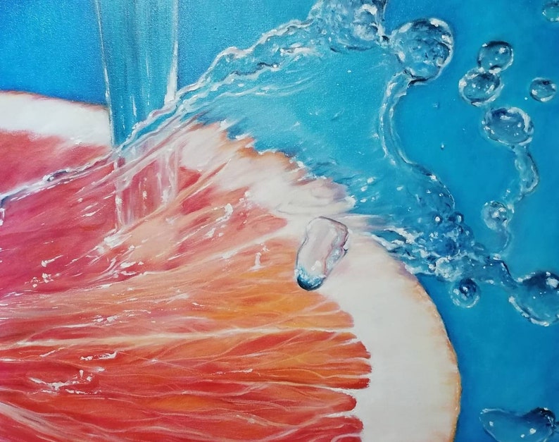 May include: A close-up of a grapefruit being rinsed under a stream of water. The water creates a spray of bubbles and droplets, highlighting the vibrant red and orange hues of the grapefruit.