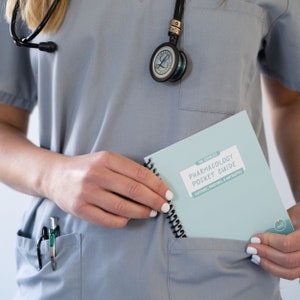 May include: A blue medical scrub top with a stethoscope and a small blue notebook that says "The Complete Pharmacology Pocket Guide - Suffixes, Prefixes, & Antidotes".