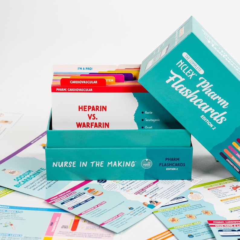 Puede incluir: Un juego de cajas turquesa de "NCLEX Pharm Flashcards, Edition 2" con una pila de tarjetas dentro. Las tarjetas est&aacute;n etiquetadas con t&eacute;rminos m&eacute;dicos como "Heparina vs. Warfarina" y "Cardiovascular". Otras tarjetas est&aacute;n esparcidas alrededor de la caja.