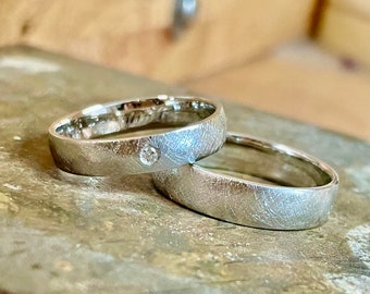 Wedding rings set in white gold brushed surface with diamond