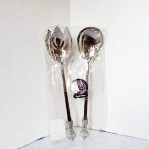 May include: A set of two silver serving utensils, a slotted spoon and a solid spoon, in a clear plastic bag with a purple label that says "Royal Albert".