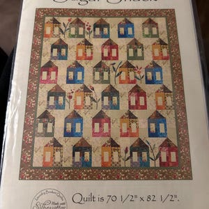 May include: A quilt pattern titled "Sugar Shack" featuring a repeating pattern of colorful houses. The quilt measures 70.5 x 82.5 inches. The pattern is by Laundry Basket Quilts.