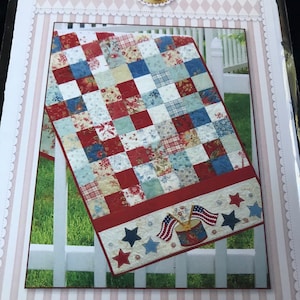 May include: A rectangular table runner with a patchwork design in red, white, and blue. The bottom border features stars, flags, and a drum. The text "American Glory Table Runner" is visible.