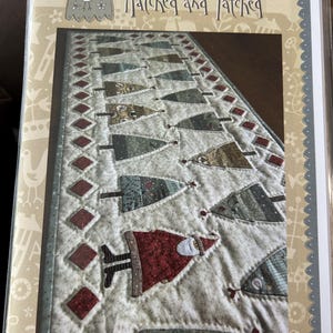 May include: A white ceramic mug with a black handle and the text "But First, Coffee" in a bold, black font. The mug is set against a blurred background, suggesting a cosy setting.