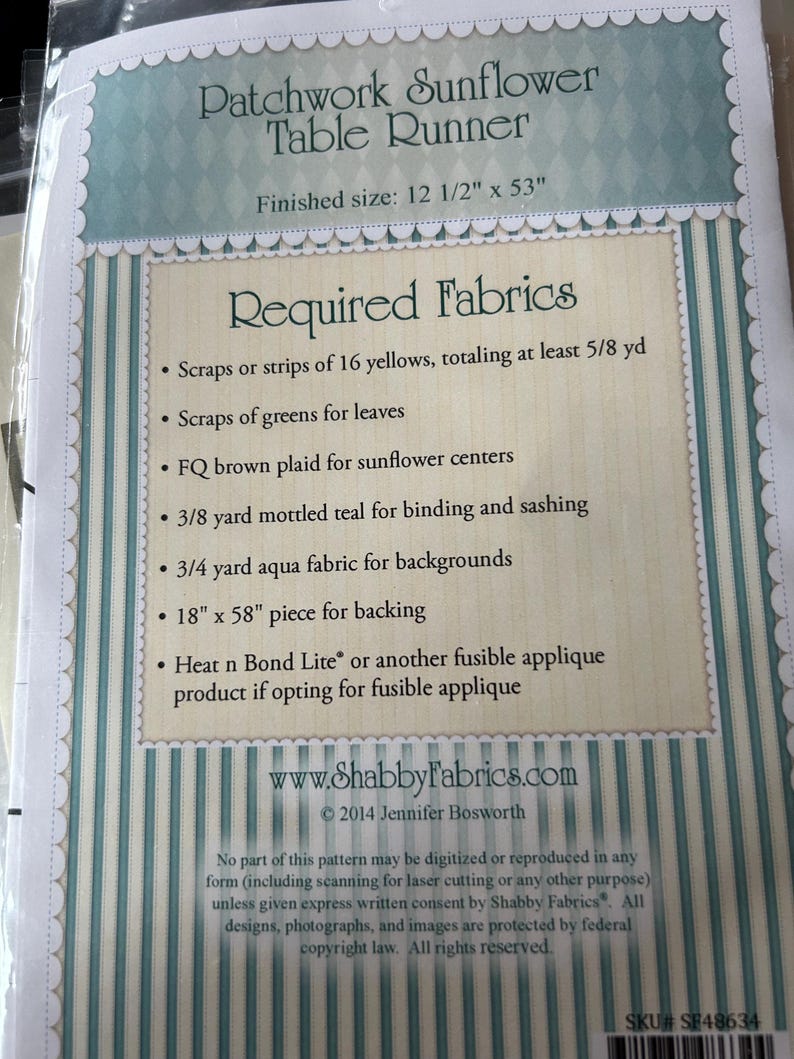 May include: A package for a Patchwork Sunflower Table Runner. The finished size is 31.75 cm x 134.62 cm. The package lists required fabrics, including yellow scraps, green scraps, brown plaid, teal, aqua fabric, and a backing piece.