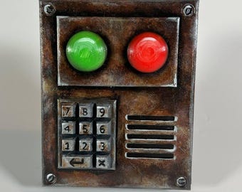 Könnte beinhalten: Eine rostige Metallplatte mit einem Tastenfeld, einem roten Knopf und einem grünen Knopf. Das Tastenfeld hat die Zahlen 1 bis 9, und die Knöpfe sind mit Pfeilen beschriftet. Die Platte ist mit "Rust lootroom" beschriftet.