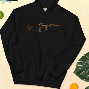 May include: Black hoodie with a brown and orange cartoon image of a rifle on the front.