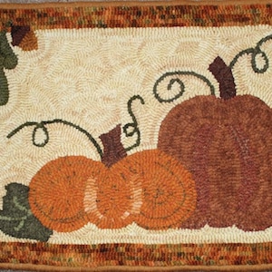 May include: A brown, orange, and green hooked rug with a design of three pumpkins and leaves. The pumpkins are arranged in a row with the largest pumpkin in the back and the two smaller pumpkins in front. The rug has a brown border.