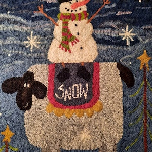 May include: A white snowman with a red and green scarf and a black top hat sits on a gray sheep with the word "SNOW" on its saddle. The background is a blue sky with white snowflakes.