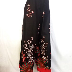 May include: Black wide-leg pants with a red and white floral print featuring bamboo and fan designs.